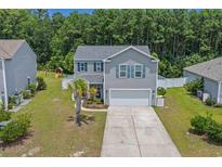 Charming two-story home with a well-manicured lawn, a two-car garage, and a beautiful tree line at 189 Harmony Ln., Myrtle Beach, SC 29588