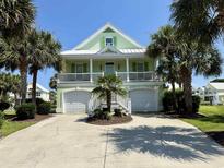 Charming two-story home with a light green exterior, white trim, a spacious balcony and a two-car garage at 312 Shelly Bay Ct., Surfside Beach, SC 29575