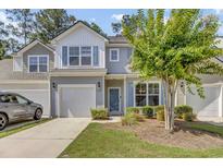 Charming two-story home featuring a garage, blue shutters, and a well-manicured lawn with a beautiful flowering tree at 315 Bulkhead Bend # 315, Carolina Shores, NC 28467