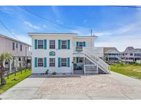 Charming two-story beach house with teal shutters and ample parking space for a relaxed coastal living experience at 329 54Th Ave. N, North Myrtle Beach, SC 29582