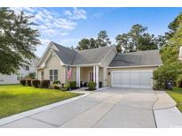 Charming single-story home featuring a well-manicured lawn, attached two-car garage, and welcoming front porch at 409 Cypress View Ave., Little River, SC 29566