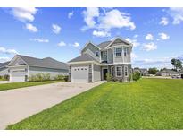 Charming two-story home features stone accents, a two-car garage, and a well-manicured lawn at 715 Hobonny Loop, Longs, SC 29568