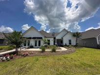 Charming one-story home featuring a beautifully landscaped yard and inviting walkway under a bright sky at 121 Eagle Claw Dr., Carolina Shores, SC 28467