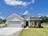 Charming one-story home with white siding, brick accents, attached two-car garage and manicured lawn at 193 Norris Ln, Loris, SC 29569