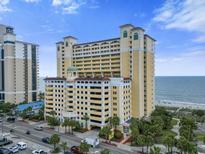 Stunning high-rise condo building with a yellow facade, offering beautiful ocean views and a convenient parking garage at 2000 N Ocean Blvd. # 1206, Myrtle Beach, SC 29577