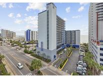 Hotel exterior with palm trees, parking and street view on a sunny day with light clouds at 2001 S Ocean Blvd. # 920, Myrtle Beach, SC 29577