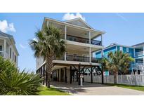 Three-story beach house on stilts with double balconies and tropical landscaping at 221 N Waccamaw Dr., Murrells Inlet, SC 29576