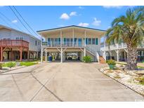 Coastal home with a large driveway, covered parking, and a white exterior with blue accents at 325 N 58Th Ave. N, North Myrtle Beach, SC 29582