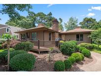 Charming home featuring a spacious deck, lush landscaping, and a brick chimney under a clear sky at 3533 Lighthouse Way, Myrtle Beach, SC 29577