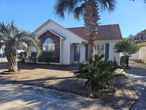 Charming single-story home featuring palm trees, brick walkway, blue shutters, and decorative window accents at 927 Edge Dr., North Myrtle Beach, SC 29582