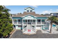 Stunning coastal home featuring a two-story design, complemented by white railing, and manicured landscaping at 1885 Pompano Dr., Garden City Beach, SC 29576
