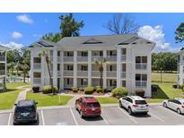 Three-story condo building featuring white exteriors, balconies, manicured landscaping, and convenient parking at 493 White River Dr. # 28-D, Myrtle Beach, SC 29579