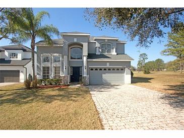 Two-story home featuring a well-manicured lawn, a paver driveway, and a two-car garage at 33953 Terragona Dr, Sorrento, FL 32776