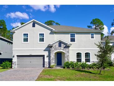 Charming two-story home boasts a stone entryway, inviting curb appeal, and a well-manicured lawn at 29912 Cypress Pointe, Deer Island, FL 32778