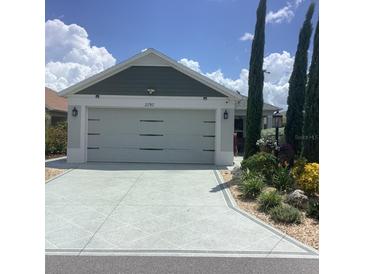 House exterior featuring a two-car garage and well-manicured landscaping at 2292 Richey Rd, The Villages, FL 32163