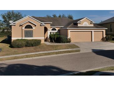 Tan house with three-car garage and lush landscaping at 510 Coventry Rd, Davenport, FL 33897
