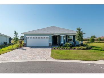 Single-story home with white garage door and landscaped lawn at 7865 Sw 89Th Cir, Ocala, FL 34481