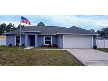 Newly built home with blue exterior, white fence, and a two-car garage at 12854 Sw 77Th Cir, Ocala, FL 34473