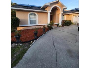 Tan house with solar panels, arched entryway, and landscaped yard at 4635 Deer Run Rd, St Cloud, FL 34772