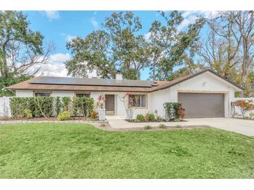 Charming single-story home with a well-manicured lawn, brick accents, and solar panels on the roof at 4539 Wild Rose Ct, Orlando, FL 32808