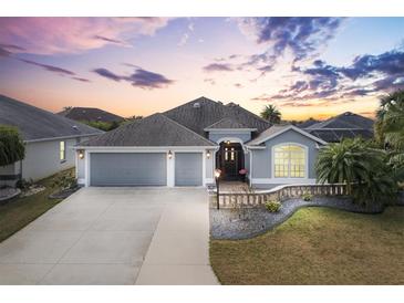 Charming single-story home with a well-manicured front yard, two-car garage, and delightful twilight sky at 3303 Ridgewood Path, The Villages, FL 32163