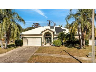 Charming single-story home featuring lush landscaping, a two-car garage, and solar panels at 603 Pinehurst Ct, Kissimmee, FL 34758