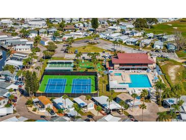 An aerial view showcases the active community with a pool, clubhouse, tennis courts, and beautiful landscaping at 9000 Us Highway 192 # 242, Clermont, FL 34714