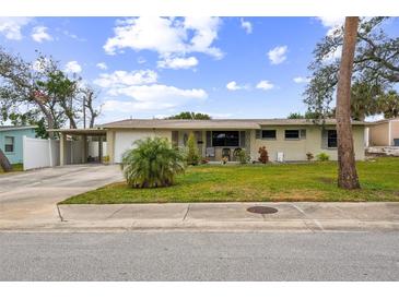 Charming single-story home featuring a large front yard with a carport and attached garage at 63 Benjamin Dr, Ormond Beach, FL 32176