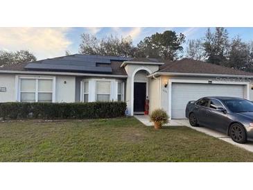 Charming single-story home with solar panels, a well-manicured lawn, and a two-car garage at 1136 Doncaster Ct, Kissimmee, FL 34758