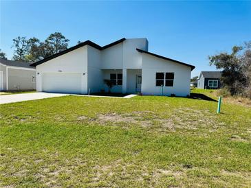 Modern home featuring a crisp white exterior, dark trim, and a well-maintained lawn on a sunny day at 1314 Congo Ct, Poinciana, FL 34759