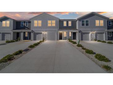 Modern townhome exterior features multiple units with attached garages, tidy landscaping, and long driveways at 6677 Sw 81St Loop, Ocala, FL 34476