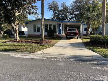 Charming single-story home featuring a driveway, carport, landscaped yard, and mature trees at 910 Orchid St, Lady Lake, FL 32159