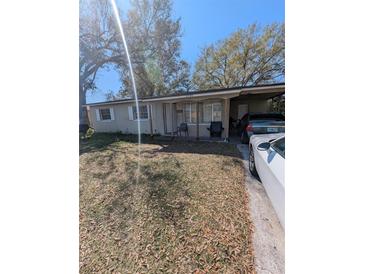 Modest single-story home with covered parking and a front porch amidst trees at 5195 Edwina St, Orlando, FL 32811