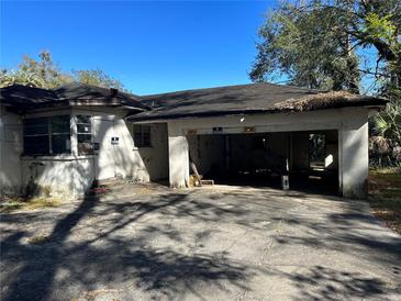 Exterior view of a dilapidated house with a two car garage and overgrown foliage at 1075 Merritt St, Altamonte Springs, FL 32701