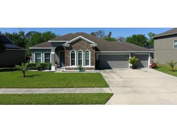 Charming home with a stone facade, well-manicured lawn, and a three-car garage, offering curb appeal at 1991 Sanderlin Point Loop, Apopka, FL 32703