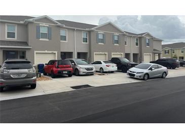 Row of townhouses with gray exteriors, garages, and various cars parked in front, showing curb appeal at 1026 Lido Dr, Howey In The Hills, FL 34737