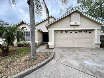 Charming single-story home boasts a two-car garage and is complemented by tropical landscaping and a well-manicured lawn at 12113 Calaboose Ct, Orlando, FL 32828