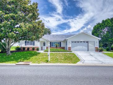 Charming single-story home with a well-manicured lawn, mature trees, and a two-car garage, perfect for suburban living at 13729 Se 89Th Ave, Summerfield, FL 34491