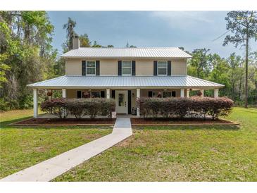 Charming two-story home with a long porch, metal roof, well-maintained landscaping, and a welcoming walkway at 3333 Se 3Rd Ave, Ocala, FL 34471