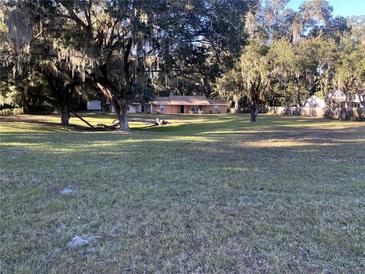 Sprawling front yard with large shade trees and a glimpse of the single story home at 3 Lakeside Dr, Ocala, FL 34482