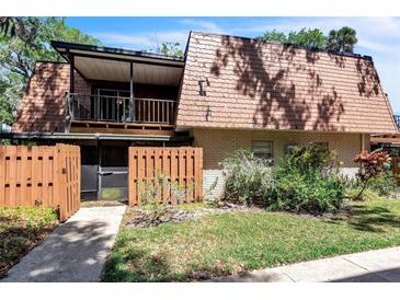 Two-story home with brick facade, balcony, fenced entry, and mature landscaping at 159 Sweetgum Ln, Port Orange, FL 32129