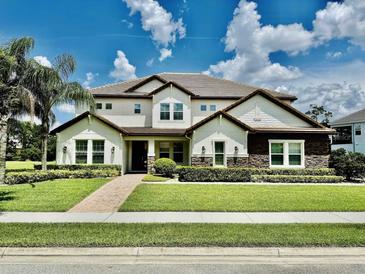 Beautiful two-story home with a manicured lawn, stone accents, and a tile roof under a sunny sky at 7443 Lake Albert Dr, Windermere, FL 34786