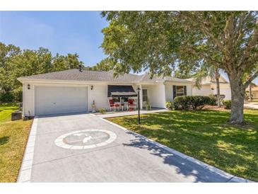 Charming single-story home featuring a well-manicured lawn, a decorative driveway, and a cozy front porch seating area at 2382 Due West Dr, The Villages, FL 32162