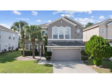 Charming two-story home featuring stone accents, a manicured lawn, and a two-car garage at 13532 Meadow Bay Loop, Orlando, FL 32824