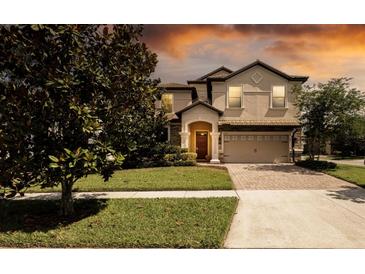 Charming two-story home with a brick driveway and well-manicured lawn at 1450 Rolling Fairway Dr, Davenport, FL 33896