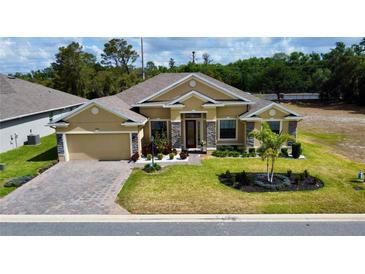 Beautiful single-story home with manicured lawn, stone accents, and a brick driveway at 1568 Cordgrass Way, Lakeland, FL 33813