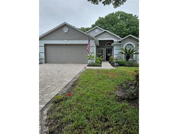 Charming single-story home featuring a two-car garage, brick driveway, and well-maintained landscaping at 3905 Westerham Dr, Clermont, FL 34711