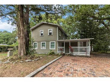 Charming two-story home with a welcoming front porch and brick driveway surrounded by lush greenery at 2508 Yale Ave, Sanford, FL 32773