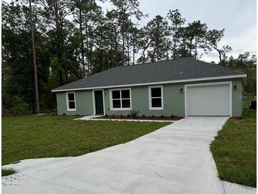 Charming single-story home featuring a well-manicured lawn, attached garage, and a classic, welcoming facade at 24202 Nw Aspen Ln, Dunnellon, FL 34432