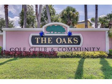 Entrance sign to 'The Oaks' Golf Club and Community with manicured lawn and colorful landscaping at 2960 Boating Blvd, Kissimmee, FL 34746